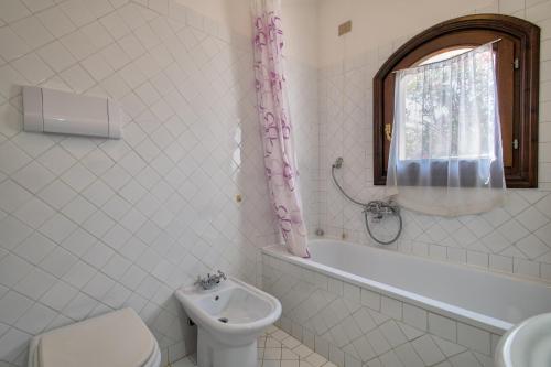 een badkamer met toilet, bad en wastafel bij Trilocale Fiordaliso in Stintino