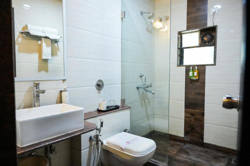a white bathroom with a sink and a toilet at Hotel Sai Jashan Shirdi - Where blessings & comfort meet in Shirdi