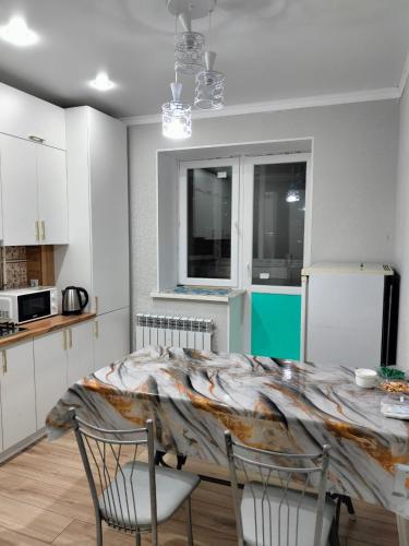 Una cocina con una mesa y dos sillas y un refrigerador. en 2ком Евро Батыс2, en Aktobe