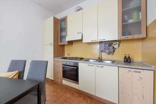 a kitchen with white cabinets and a sink and a table at Suite panoramica in Guest House in Moltrasio