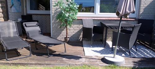 a patio with a table and chairs and an umbrella at Kleine Auszeit am Meer in Büsum