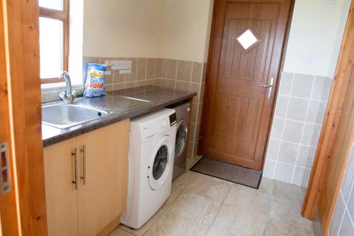 a kitchen with a washing machine and a sink at Aberystwyth Enlli Cottage in Llanilar