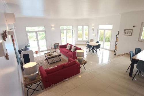 a living room with a red couch and a table at Casa Condor - Moradia com piscina a 5 min da praia in Lourinhã