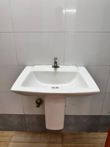 a white sink in a bathroom with a trash can at SS Grand with swimming pool in Puducherry