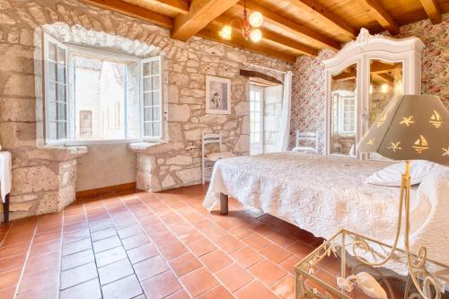 ein Schlafzimmer mit einem Bett in einem Steingebäude in der Unterkunft Maison de Campagne à Cunèges in Cunèges