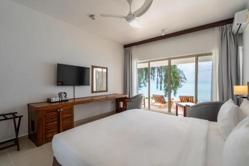 a bedroom with a large white bed and a balcony at Nungwi Dreams by Mantis in Nungwi