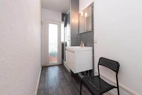 bagno con lavandino e sedia nera di Appartement 3 chambres Wifi Lorient Centre a Lorient