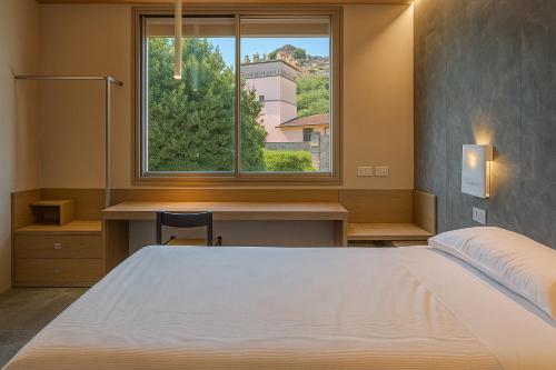a bedroom with a bed and a desk and a window at Hotiday Lerici Trebiano in Lerici