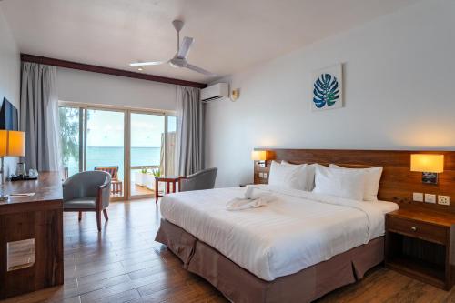 a hotel room with a bed and a desk and a window at Nungwi Dreams by Mantis in Nungwi