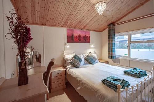 a bedroom with a bed and a desk and a window at Lakeside 1, White Cross Bay, Windermere in Windermere