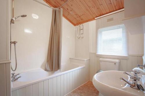 a bathroom with a tub and a sink and a toilet at Lakeside 1, White Cross Bay, Windermere in Windermere