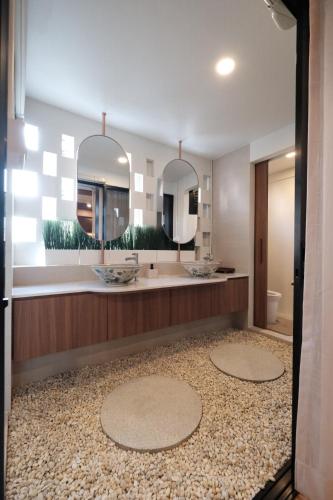a bathroom with two sinks and two mirrors at The Shantipan Mandala - Cozy City Retreat 400m from BTS Station in Bangkok