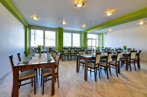a restaurant with wooden tables and chairs and green walls at Hotel Klar in Liptovský Mikuláš