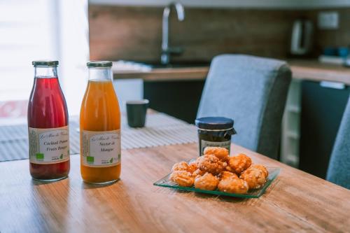 Saint-Jean-le-CentenierにあるMagnifique Appartement Climatisation Parking Gratuitのテーブルの上にジュース2本と食べ物の皿が置かれている