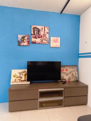 a living room with a tv on a blue wall at Summer Suites KLCC by CozyNest in Kuala Lumpur
