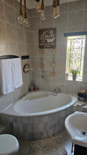 ein Badezimmer mit großer Badewanne und Waschbecken in der Unterkunft Rose Cottage Vintage room in Pretoria