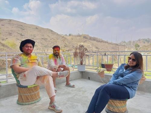two men and a woman sitting on a balcony at Himkosi Farm by the River in Almora