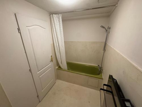 a small bathroom with a tub and a door at Modern and old T2 in Condrieu