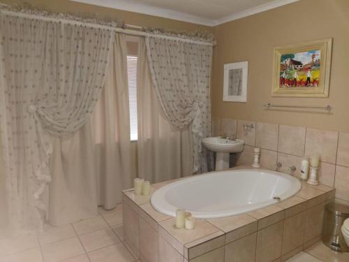 a bathroom with a large tub and a sink at Cranberry Cottage in Kathu