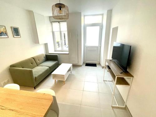 a living room with a couch and a television at Les Clés de Saint-Pierre in Saint-Pierre-Église