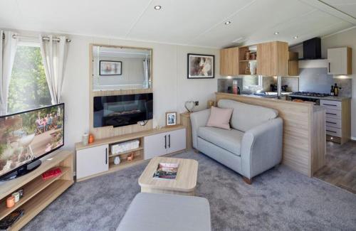 Una sala de estar con un sofá y un televisor de pantalla plana. en Autumn Lakefront Retreat - Free Fishing, en Amotherby