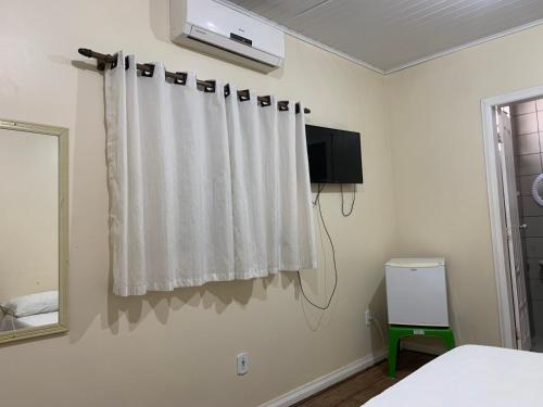 a bedroom with a white curtain and a tv at Hotel Casa do Ivo Orla in Santarém