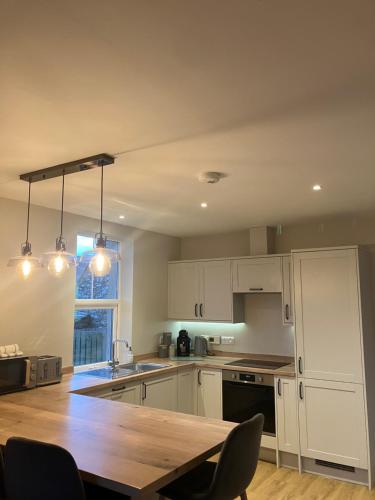 a kitchen with white cabinets and a wooden table at Quina Holiday Home in Finstown