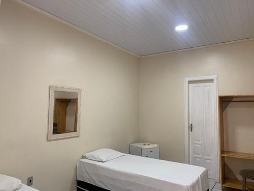 a white room with two beds and a mirror at Hotel Casa do Ivo Orla in Santarém