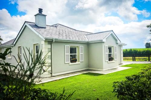 a white house with a grass yard at Devlin's cottage near Slane in Slane