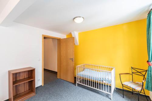 a bedroom with a crib and a yellow wall at Bacchus Holiday Homes in Bacharach
