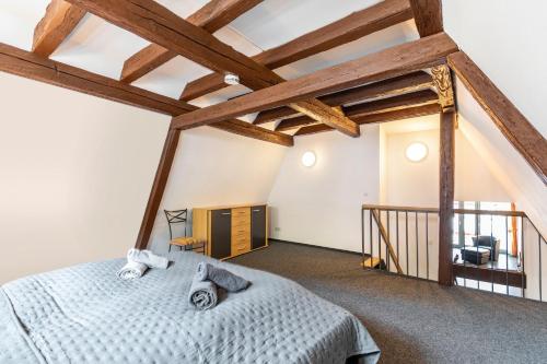 a bedroom with a bed in a loft with wooden beams at Bacchus Holiday Homes in Bacharach
