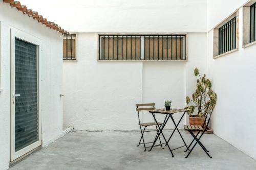 a table and two chairs next to a white wall at Estrela House by Homing in Lisbon