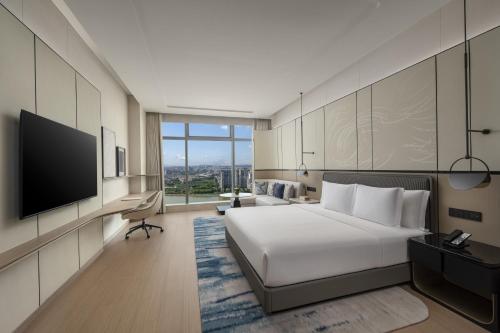 ein Hotelzimmer mit einem Bett und einem Flachbildfernseher in der Unterkunft Crowne Plaza Guangzhou Window of Canton-Free Shuttle Bus Available during Canton Fair Period in Guangzhou
