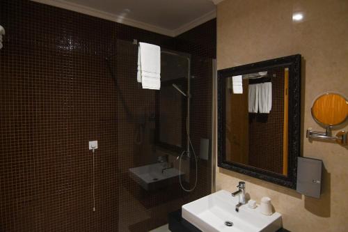 a bathroom with a sink and a shower and a mirror at QH Praia de Quiaios in Praia de Quiaios