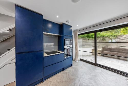 a kitchen with blue cabinets and a large window at Coach House in London