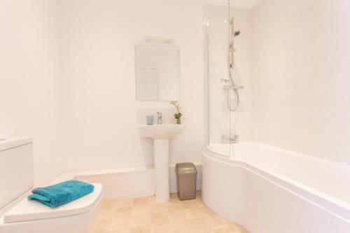 a white bathroom with a tub and a sink and a toilet at Contemporary 2 Bedroom Apartment in Oxford, Easy Access to City Centre & JR Hospital in Oxford