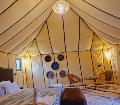 a tent with two chairs and a bed in a room at Merzouga Marvelous Camp in Merzouga