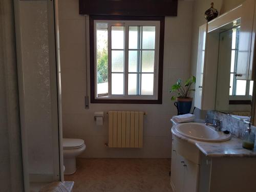 a bathroom with a sink and a toilet and a window at Casa Esmeralda in Borbén