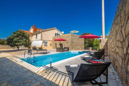 a swimming pool with chairs and umbrellas next to a house at Villa Mediteran with private pool in Vrh