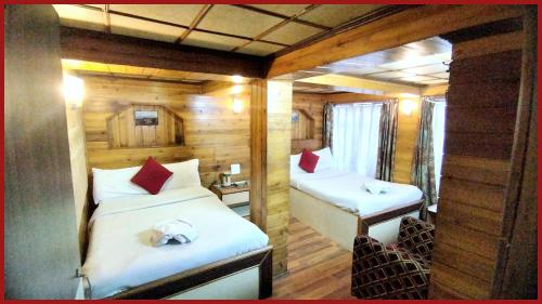 a bedroom with two beds in a room with wooden walls at A Top Rated Hotel B-R-O-A-D-A-Y - Mall Road - Luxury & Spacious Room - Book Now in Darjeeling