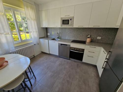 a small kitchen with white cabinets and a table at Casa en la playa de Panxón in Nigrán