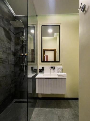 a bathroom with a sink and a mirror and a shower at Kazakhstan Hotel in Almaty