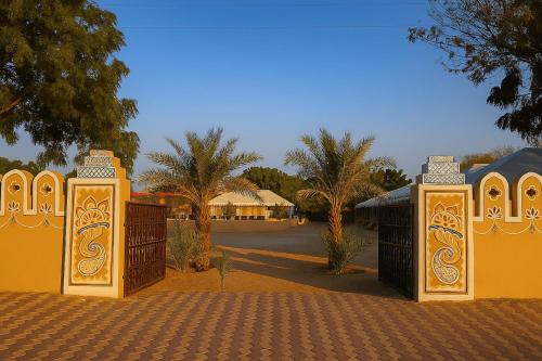 a gate in a driveway with a house in the background at The Desert Resort Jaisalmer in Jaisalmer