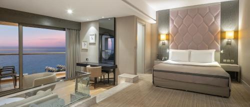 a bedroom with a bed and a desk with a view at Elexus Hotel Resort & Spa & Casino in Kérynia