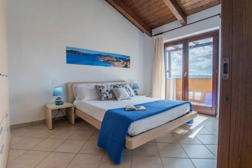 a bedroom with a bed and a large window at Domu Bonora - Relax among Red Rocks and Pool in Costa Paradiso