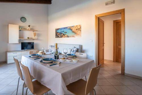 a dining room table with a white table cloth and chairs at Domu Bonora - Relax among Red Rocks and Pool in Costa Paradiso