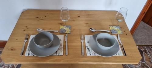 a wooden table with two plates and two wine glasses at The Creamery High Harrington in Harrington