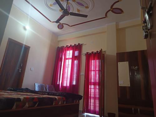 a bedroom with red curtains and a ceiling fan at Sharma Restaurant And Hotel in Bilāspur