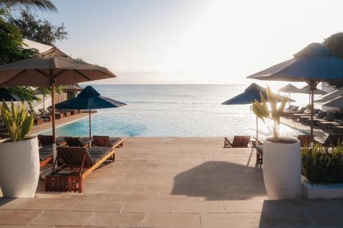 a beach with chairs and umbrellas and the ocean at Nungwi Dreams by Mantis in Nungwi