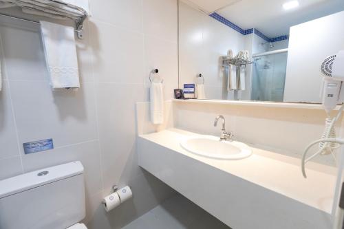 a bathroom with a sink and a toilet and a mirror at Mais Hotel Aeroporto Salvador in Lauro de Freitas